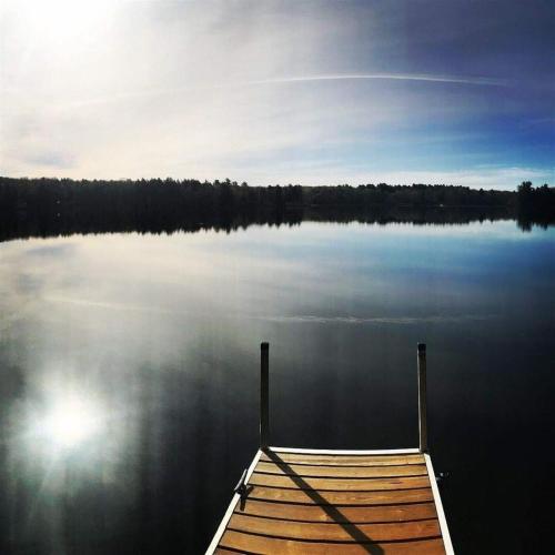 a dock on a lake with the sun reflecting on the water at ANNABESSACOOK RETREAT LIMIT 8 home in Winthrop