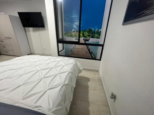 1 dormitorio con cama blanca y ventana grande en Modern apartment/Studio, en Pereira