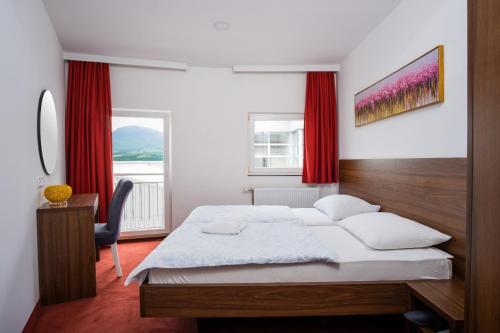 a bedroom with a bed and a desk and red curtains at Kašmir in Bugojno