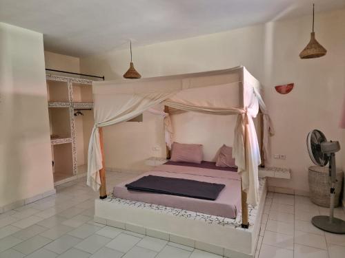 a bedroom with a bed with a canopy at Le Paradis in Nianing