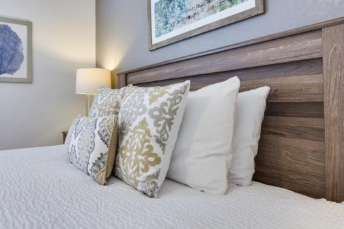 een bed met witte kussens en een houten hoofdeinde bij Penthouse Utopia condo in Orlando