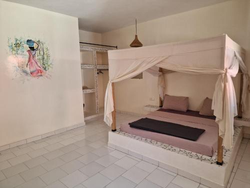 a bedroom with a bed with a canopy at Le Paradis in Nianing