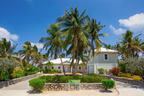 a house with palm trees in front of it at Coconut Beach by Grand Cayman Villas & Condos in Driftwood Village