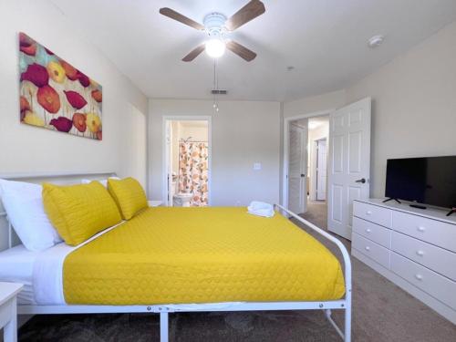 1 dormitorio con cama amarilla y TV de pantalla plana en 4 Bedroom Town Home Near Disney townhouse en Kissimmee