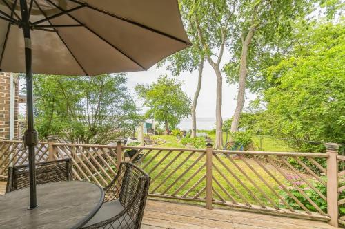 eine Holzterrasse mit einem Tisch und einem Sonnenschirm in der Unterkunft Relaxing Luxurious Waterfront townhouse in Hampton