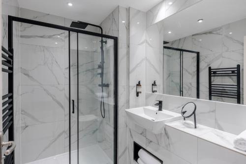 a white bathroom with a shower and a sink at Shepherds Bush - Your Apartment in London