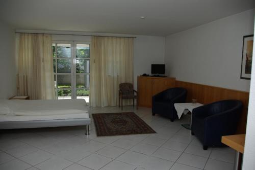 1 Schlafzimmer mit einem Bett, 2 Stühlen und einem Fenster in der Unterkunft Hotel Alte Brücke in Bad Homburg vor der Höhe