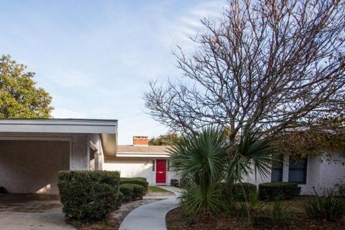 a house with a red door and a tree in front of it at ROANOKE COTTAGE home in Jekyll Island