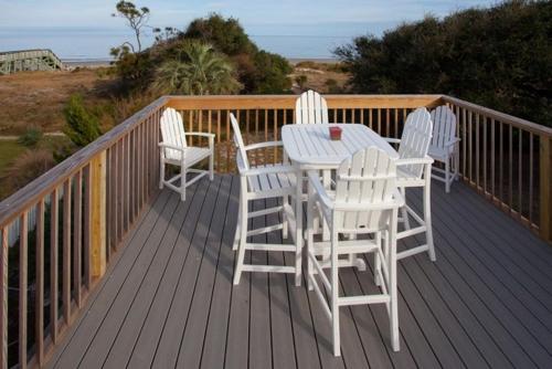 a deck with a table and four chairs on it at ROANOKE COTTAGE home in Jekyll Island