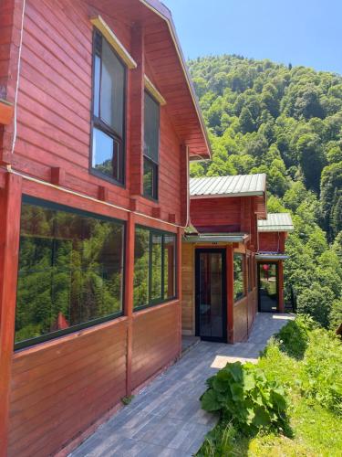 a wooden house with a deck and mountains in the background at Ayder Villa Gencal in Ayder Yaylasi