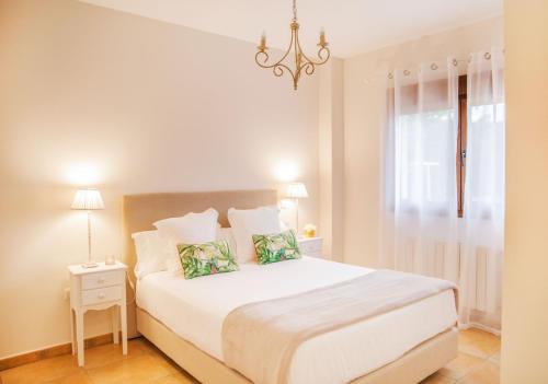 een witte slaapkamer met een groot wit bed en een kroonluchter bij Casa amplio jardín próximo al Parque Cabarceno in Penagos
