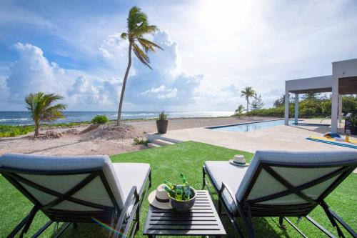 a patio with a table and chairs and the ocean at Wind Upon The Waves by Grand Cayman Villas & Condos in North Side