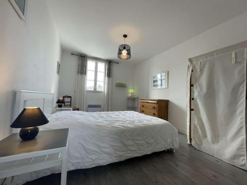 una camera con letto e tavolo con lampada di Maison Saint-Martin-de-Ré, 3 pièces, 4 personnes - FR-1-246C-26 a Saint-Martin-de-Ré