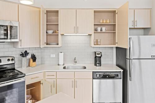 a kitchen with wooden cabinets and a white refrigerator at Placemakr Premier SoBro in Nashville