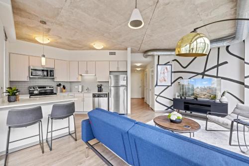 a living room with a blue couch and a kitchen at Placemakr Premier SoBro in Nashville