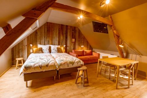 een slaapkamer met een bed, een bank en een tafel bij B&B Stefans Pottery in Poperinge