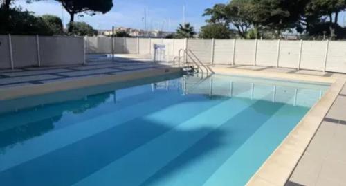 een zwembad met blauw water voor een hek bij studio pour 4 personnes proche du port et des plages in Cap d'Agde