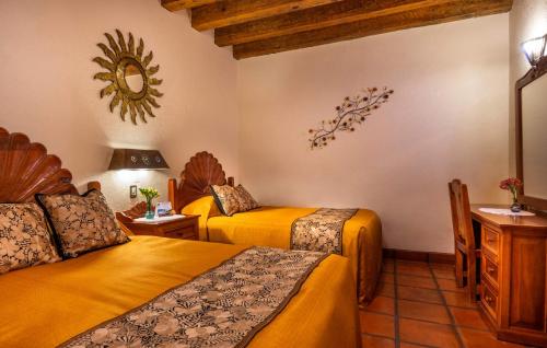 a hotel room with two beds and a mirror at Hotel Pueblo Magico in Pátzcuaro