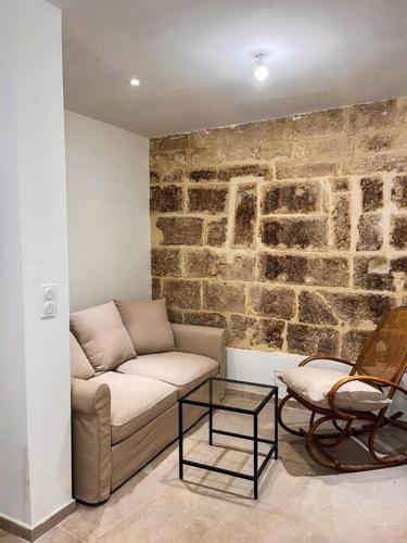 een woonkamer met een bank en een stenen muur bij Appartement charmant et calme dans l’Hérault in Poussan