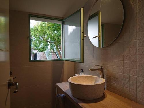 ein Bad mit einem Waschbecken, einem Spiegel und einem Fenster in der Unterkunft Casa Pozo Tarama in Casavieja