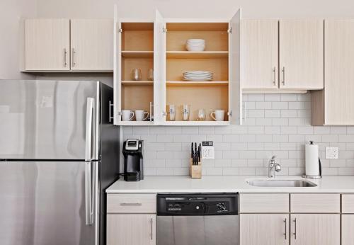 a kitchen with white cabinets and a stainless steel refrigerator at Placemakr Premier SoBro in Nashville