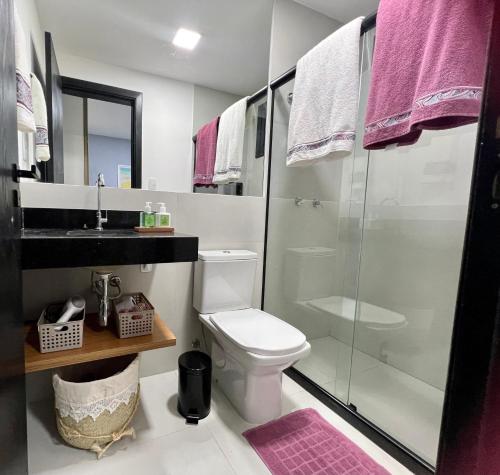 uma casa de banho com um WC e uma cabina de duche em vidro. em Village encanto - 2 quartos, luxo, térreo e lindo na Praia do Forte na Praia do Forte