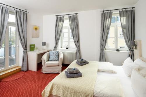 a bedroom with two beds and a chair and windows at Pension Kleine Residenz in Weimar