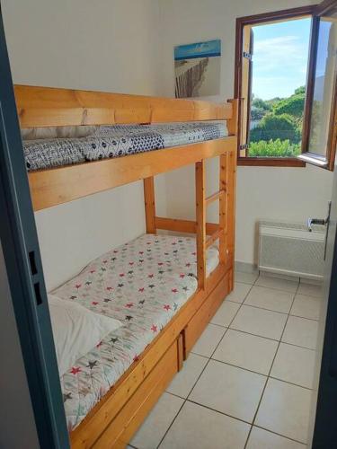 deux lits superposés dans une chambre avec fenêtre dans l'établissement Appt bord de mer deux chambres, clim, parking, piscine, à Argelès-sur-Mer