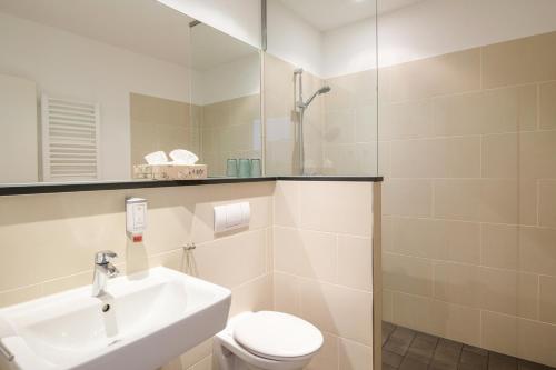 ein Badezimmer mit einem Waschbecken, einem WC und einem Spiegel in der Unterkunft Pension Kleine Residenz in Weimar