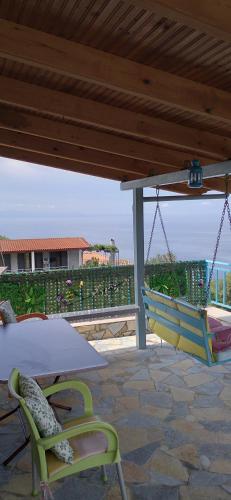 a patio with a swing and a table and chairs at Villa Luiza Piqeras in Piqeras
