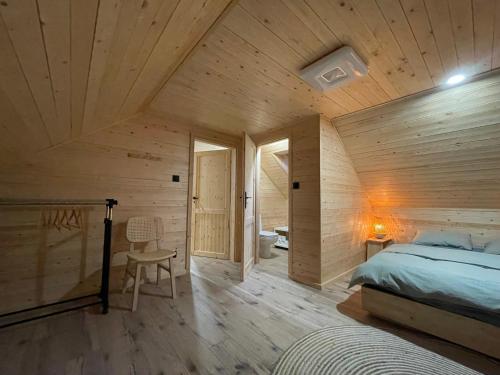 1 dormitorio con 1 cama y pared de madera en U Progu Lasu, 