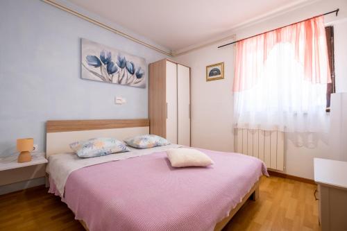 a bedroom with a bed with a pink blanket and a window at Guesthouse Mirjana in Premantura
