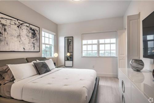 a white bedroom with a large bed and windows at Dahlia - The Designer Townhome in Lake Worth