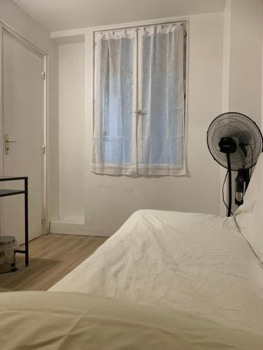 a white bedroom with a bed and a window at Chambre privée avec partage des espaces communs in Créteil