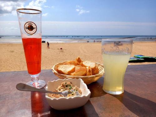 - une table avec une assiette de nourriture, une boisson et un panier de pain dans l'établissement Beau logement proche plage et centre-ville, à La Tranche-sur-Mer
