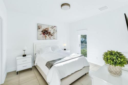 - une chambre blanche avec un lit blanc et une plante dans l'établissement Lilly at Aviara Lake Worth, à Lake Worth