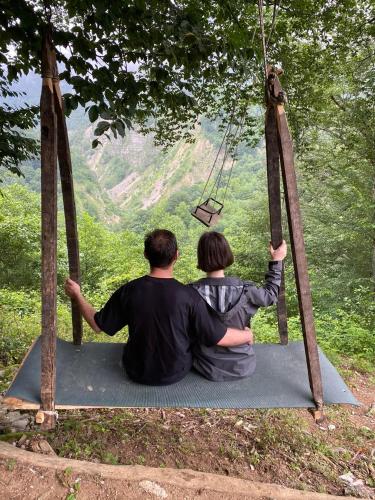 a man and a woman sitting on a swing at Guest House Balda in Martvili
