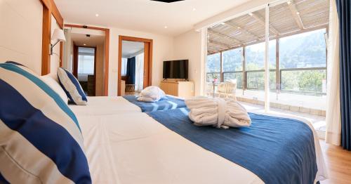 two beds in a bedroom with a large window at Los Geranios in Port de Soller
