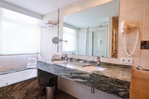 a bathroom with a sink and a tub and a mirror at Los Geranios in Port de Soller