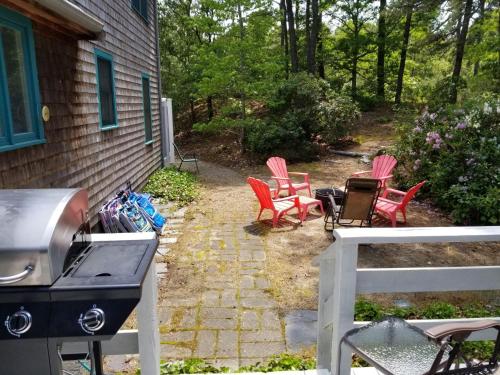 a backyard with red chairs and a grill and a house at 1325 Bridge Road Eastham Cape Cod - - Turtle Dreams in Eastham