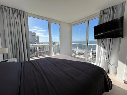 1 dormitorio con 1 cama grande y ventanas grandes en Espectacular Departamento Premium en Playa Grande frente al mar en Mar del Plata