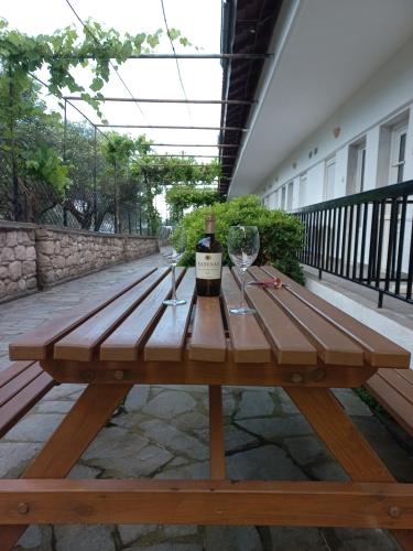 Skála Alykís的住宿－PydnaRooms，一张带一瓶葡萄酒和玻璃杯的木制野餐桌