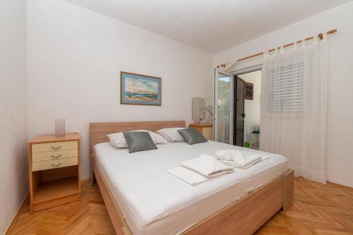 a bedroom with a large white bed and a window at Apartments Marsela in Tučepi