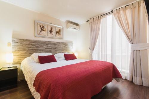 VR Suite Santiago في سانتياغو: غرفة نوم بسرير كبير مع بطانية حمراء