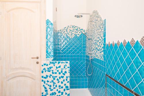 e bagno piastrellato blu con doccia e servizi igienici. di Maison Chloe a La Maddalena