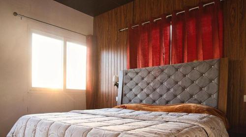 a bedroom with a large bed and a window at NamaStay Himalayas, KANATAL in Kanatal