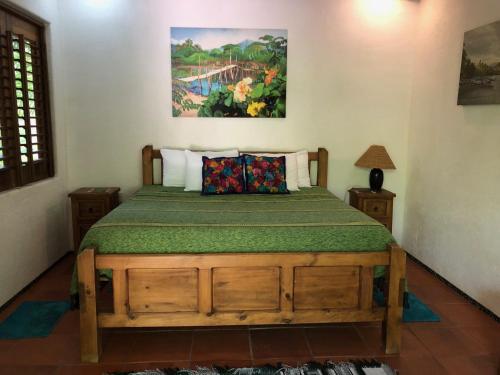 1 dormitorio con cama de madera y manta verde en Casita Linda, a luxury house near the beach!, en Zihuatanejo