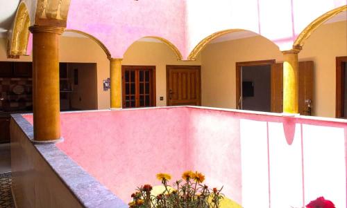 een gebouw met een roze muur en zuilen en bloemen bij Akwaba lodge in Sale