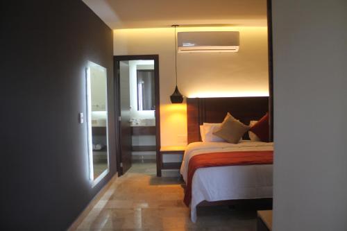 a bedroom with a bed and a mirror and a window at Hotel veinti 3 Tapachula in Raymundo Enríquez