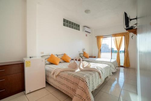 a bedroom with two beds with orange pillows and a window at Hostal Tongo Reef in Puerto Baquerizo Moreno